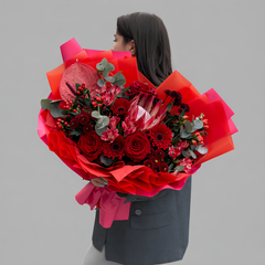 Красный букет из роз, гербер, протеи и антуриума в дизайнерской упаковке