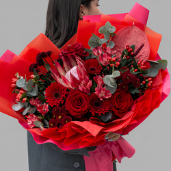 Красный букет из роз, гербер, протеи и антуриума в дизайнерской упаковке